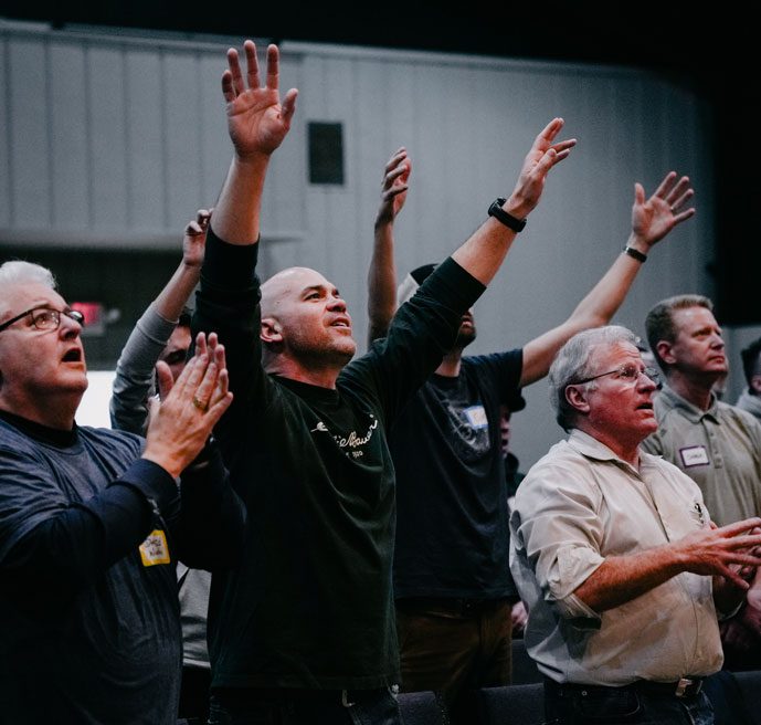 A group of people standing up with their hands raised.