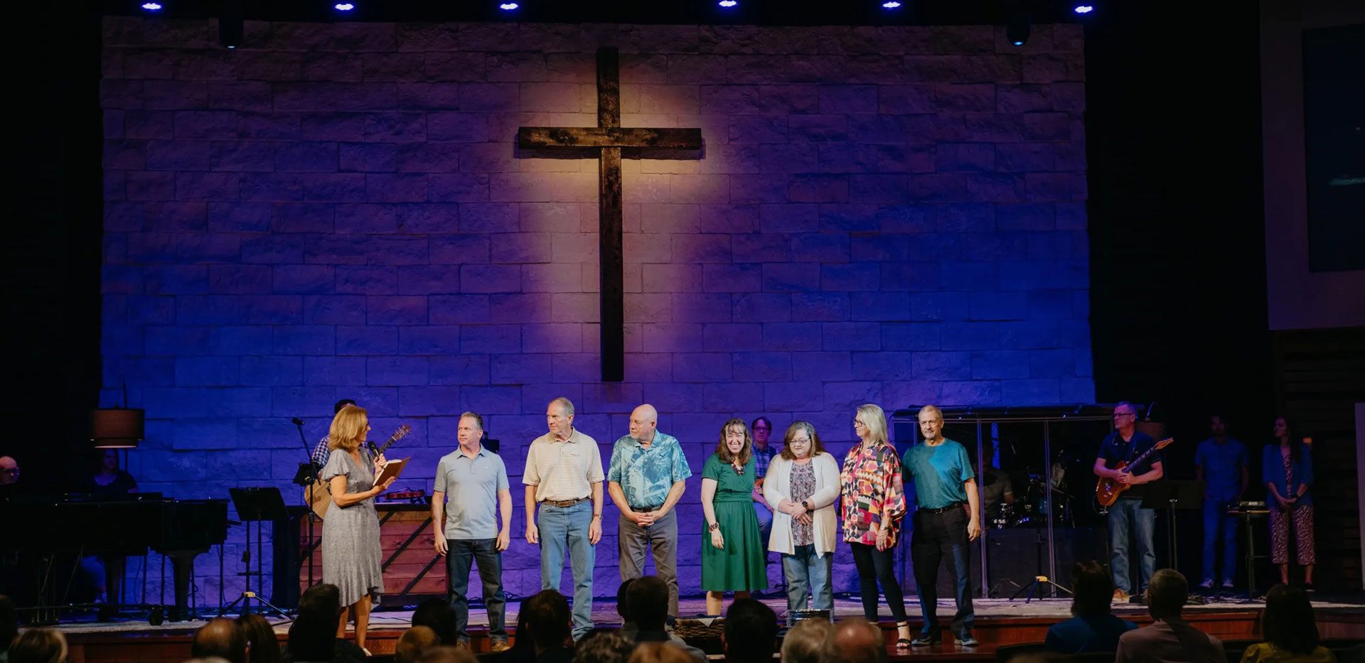 A group of people standing on stage in front of a cross.