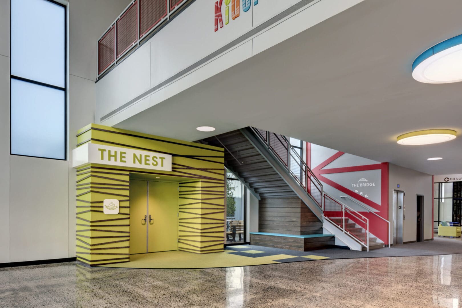 A lobby with stairs and a sign that says " the nest ".