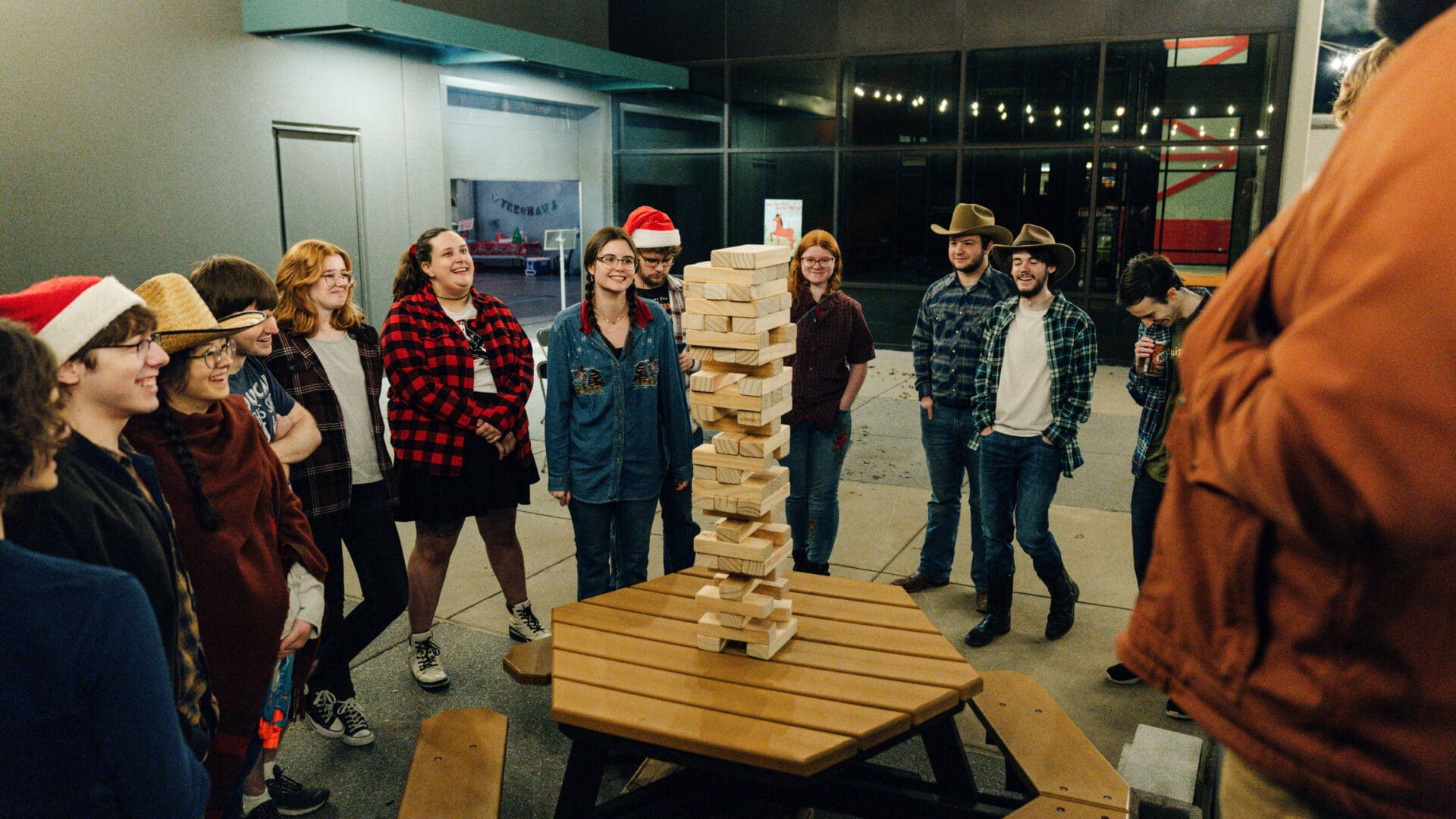 A group of people standing around a table with a tower made out of pizza boxes.