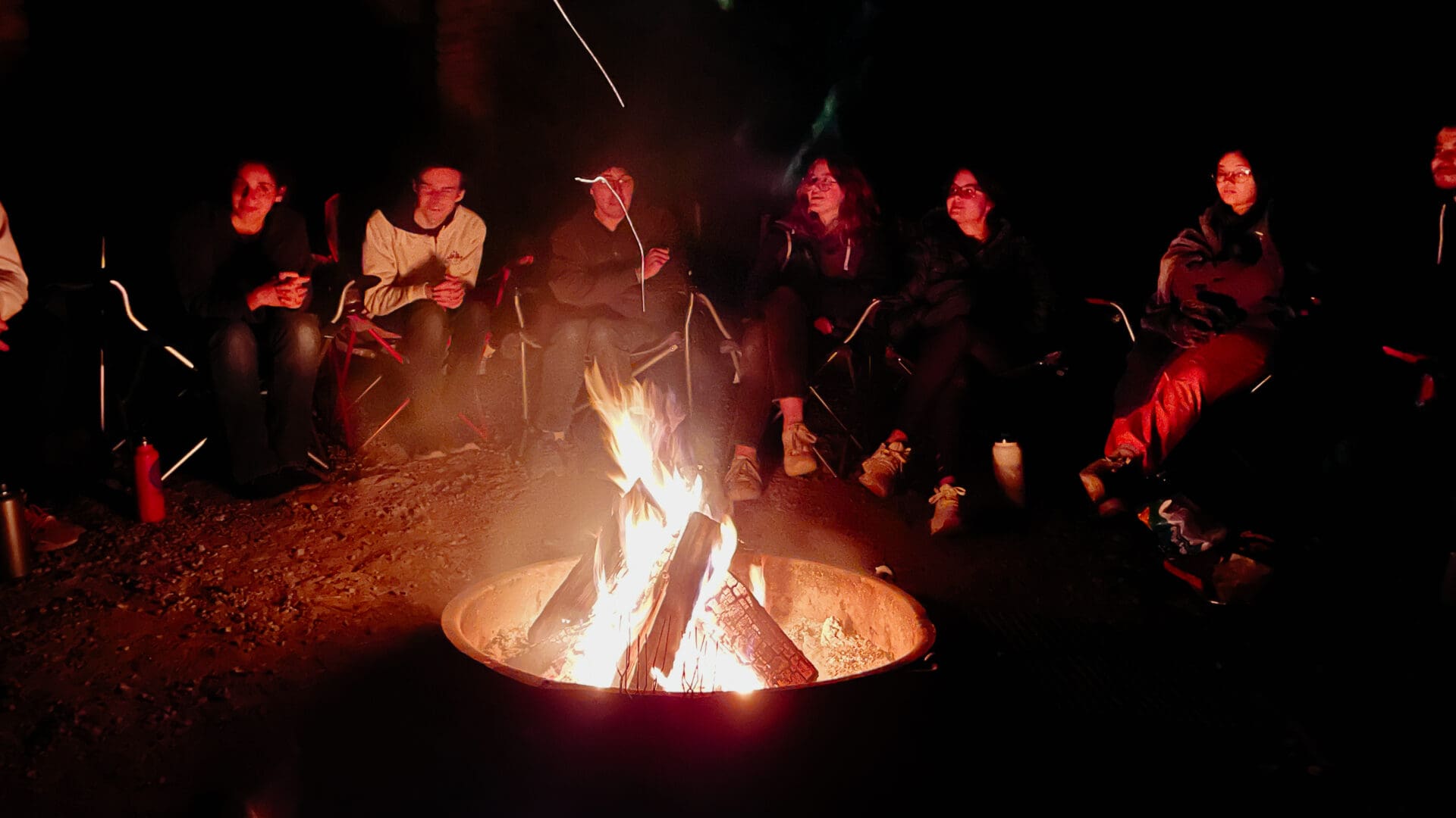 A group of people sitting around a fire pit.