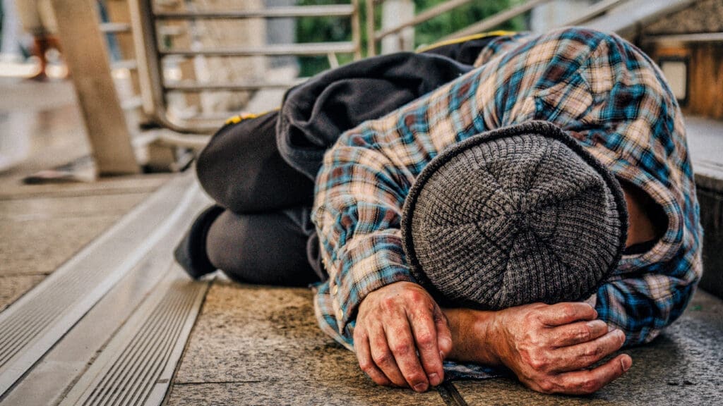 poor homeless beggar sleeping on pathway floor in suffering of unemployment asking for help