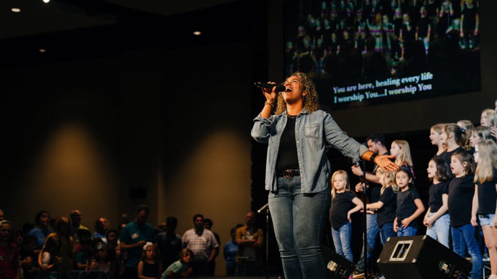 Worship Arts volunteer singing from the stage.