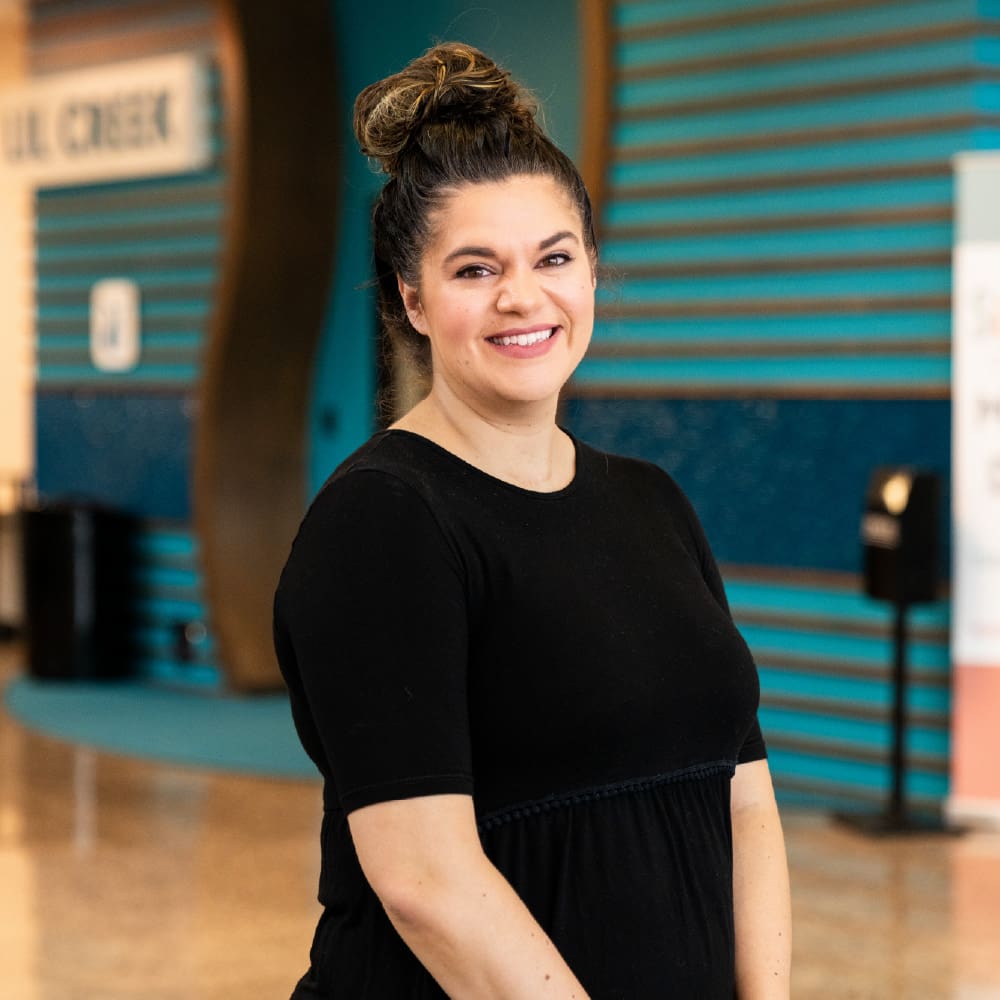 Smiling woman in black dress, indoor setting.