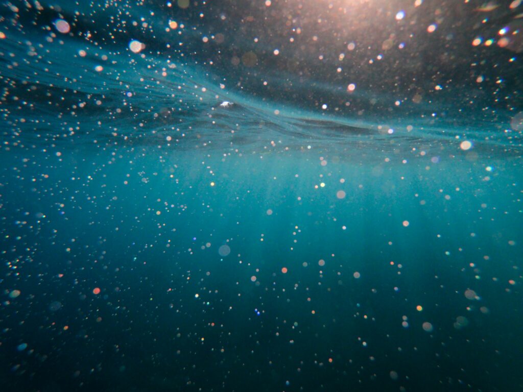 Underwater scene: shimmering particles in teal water.