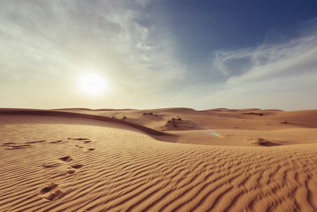 Sunset over sandy desert dunes.