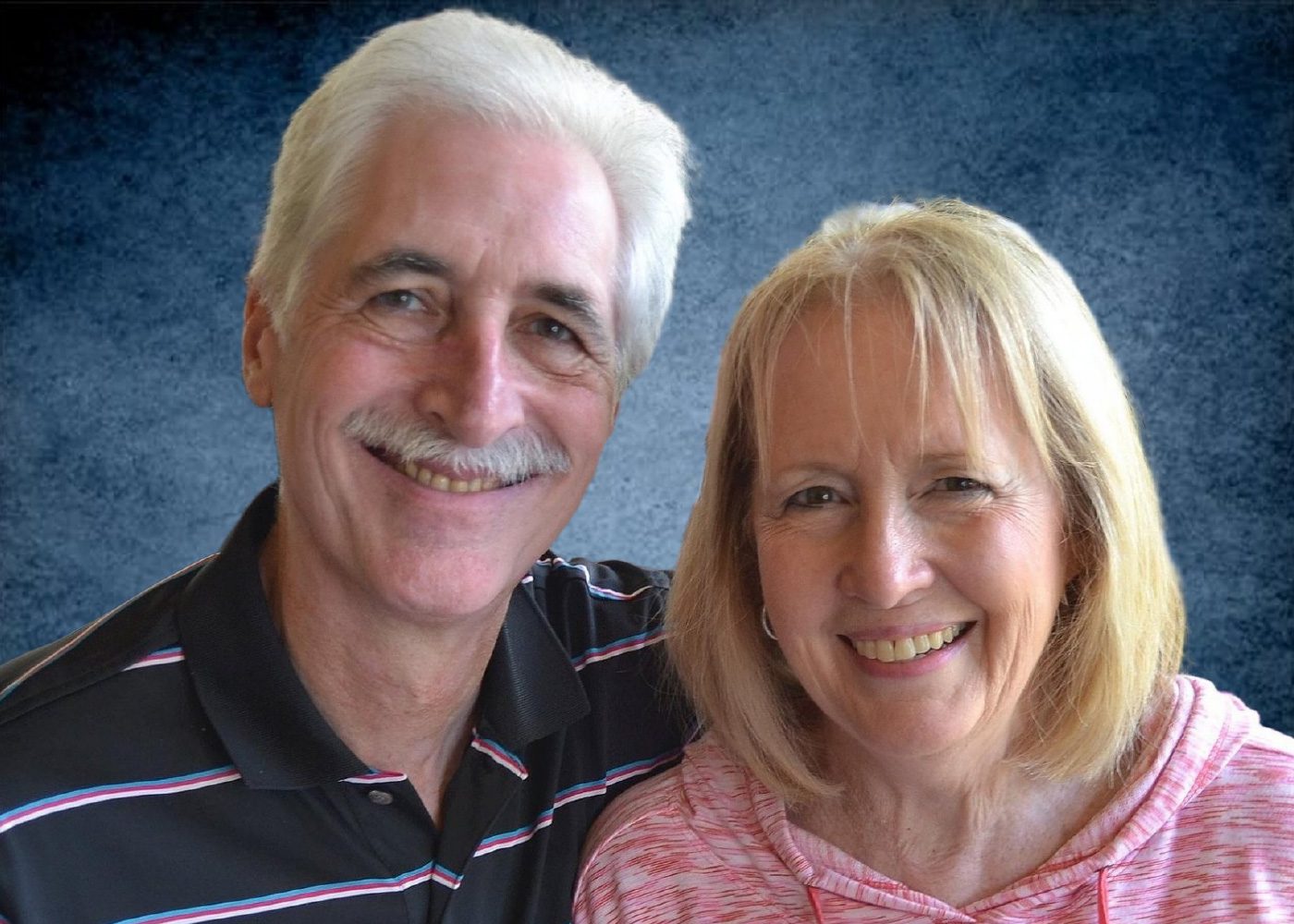 Smiling couple posing against a blue background.