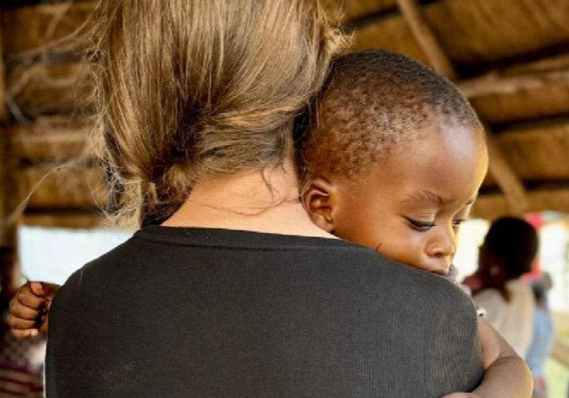 Woman holding young child in arms.