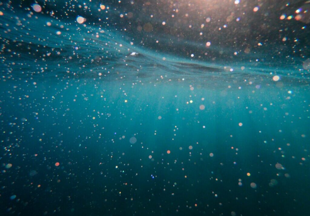 Underwater scene: shimmering particles in teal water.