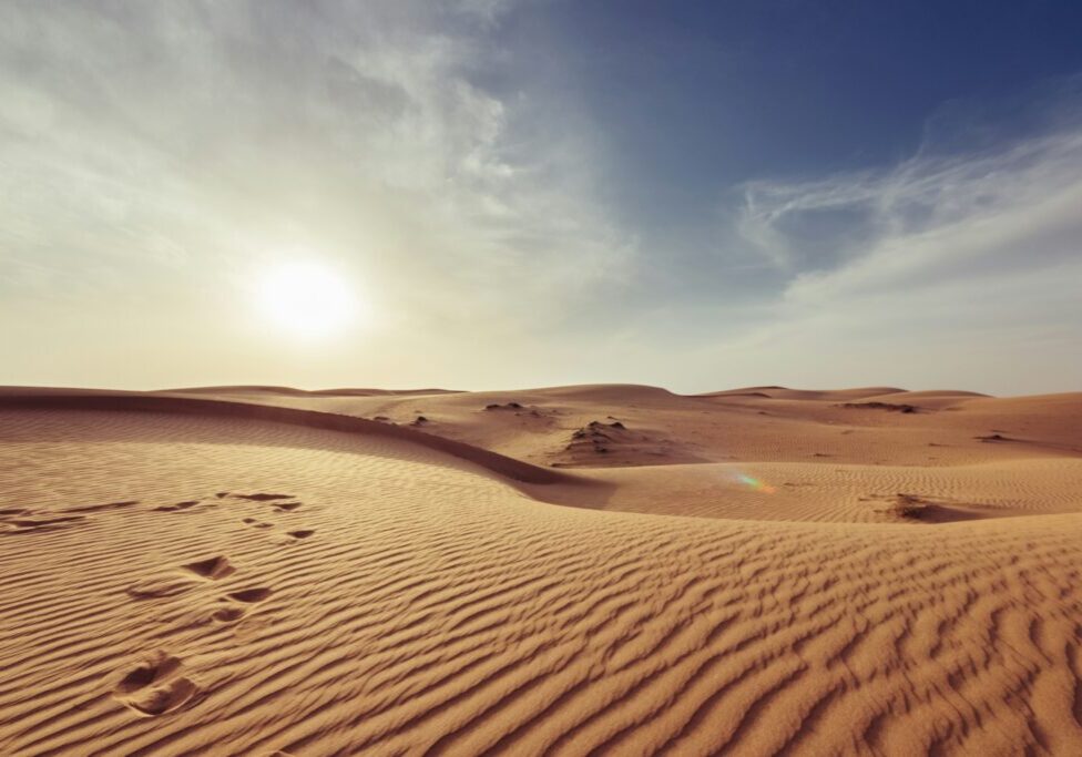 Sunset over sandy desert dunes.